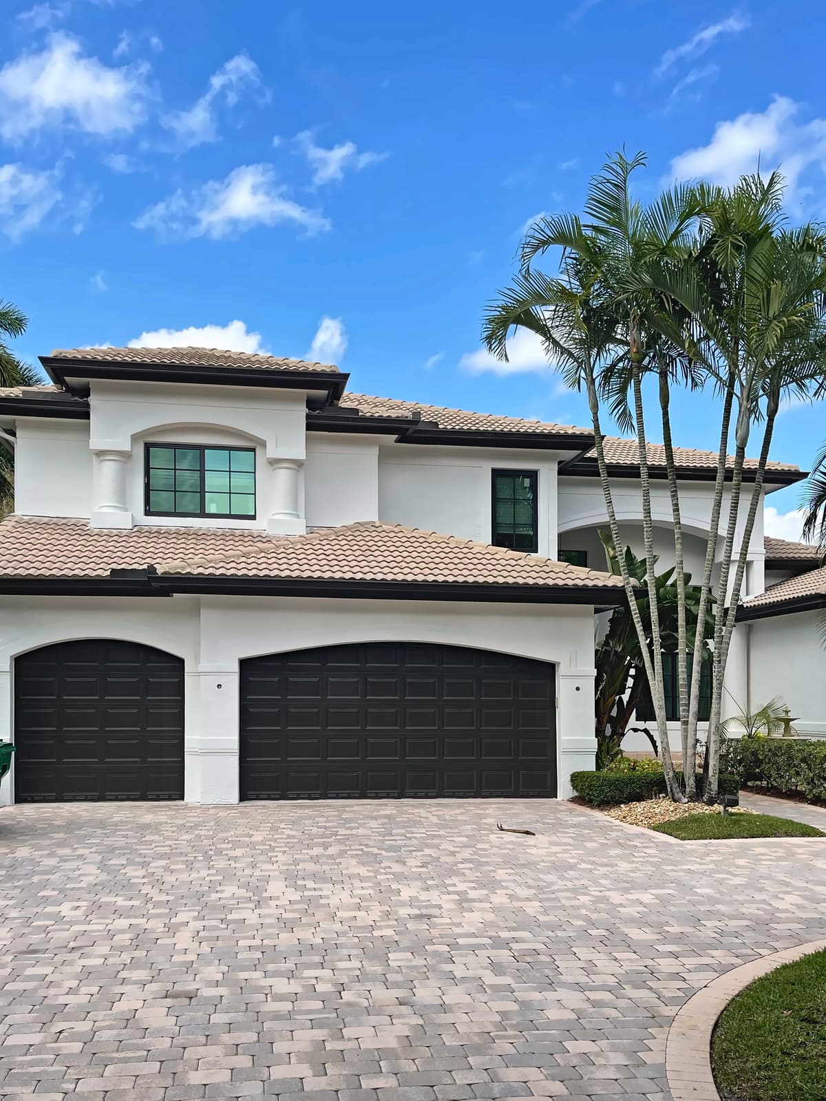 Two-story home with a tile roof, windows and two dark garage doors